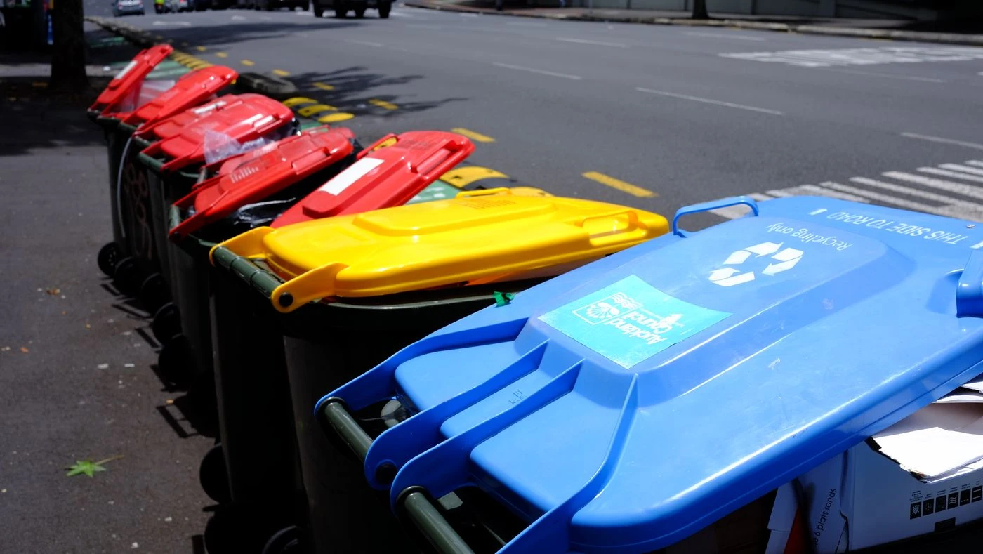 Wheeled garbage and recycling carts lined up along a curb for collection.