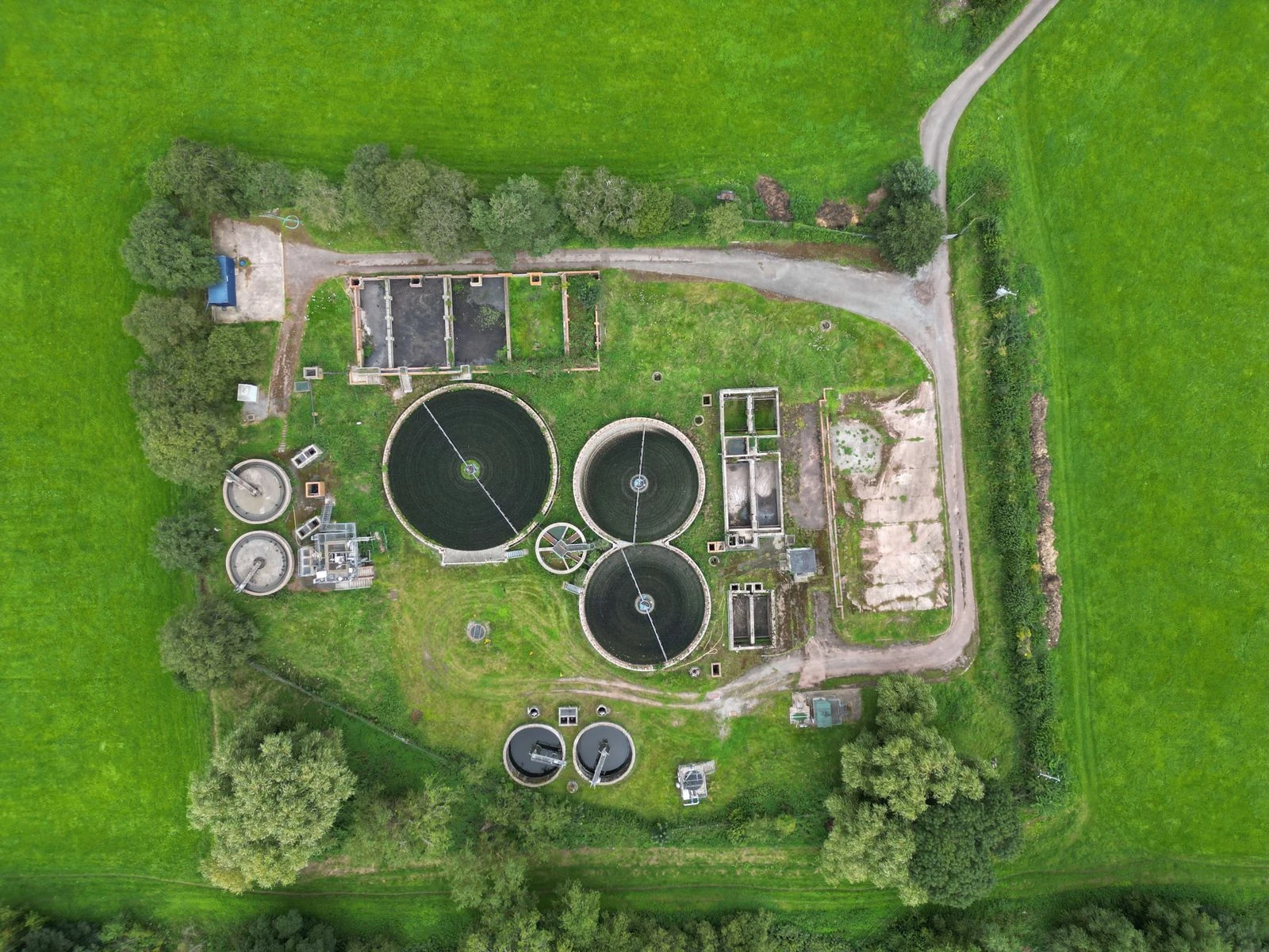 Aerial view showing the circular clarifiers, treatment tanks, and access roads of a wastewater facility.